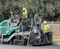 Close-up of an asphalt paver machine laying fresh asphalt on a road.