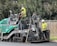A construction worker operating a paving machine on a newly asphalted road.