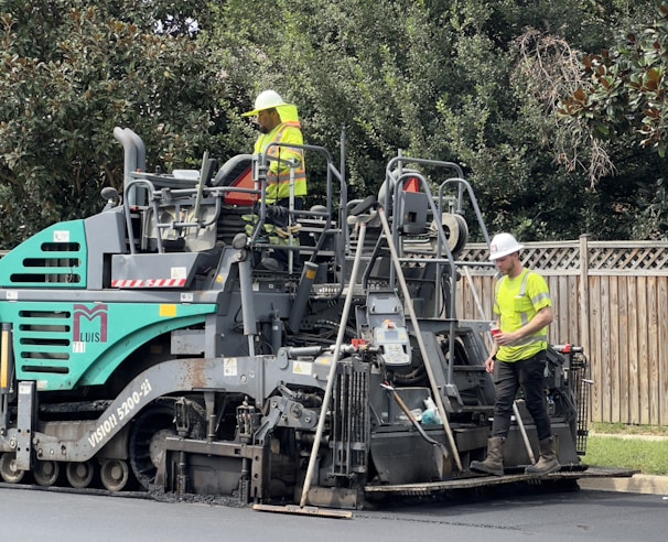Road construction site showing heavy machinery and smooth asphalt laying.