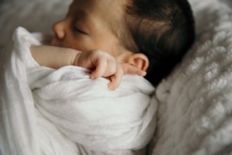 a baby wrapped in a white blanket sleeping