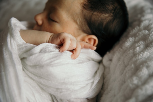 a baby wrapped in a white blanket sleeping