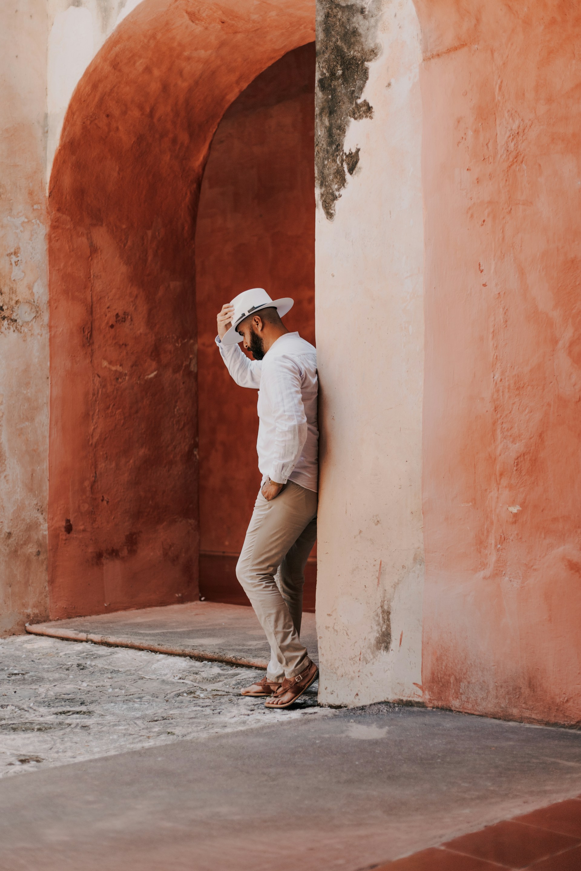 Man leans against a peach-colored archway.
