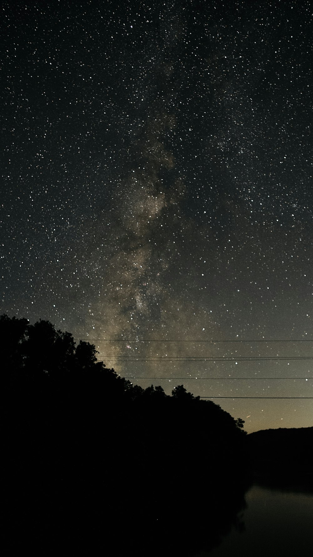 the night sky is filled with stars above a body of water