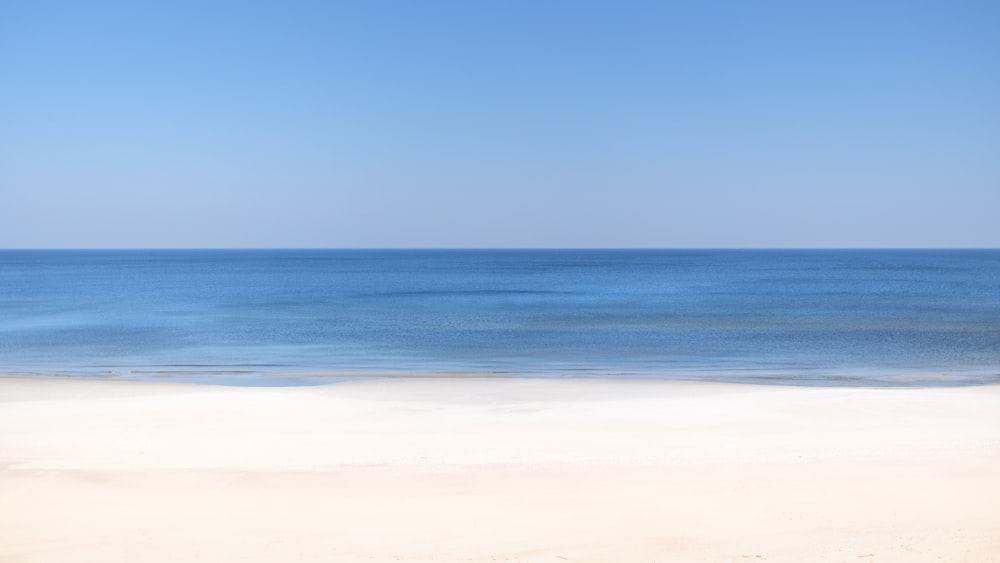an empty beach with a blue ocean in the background