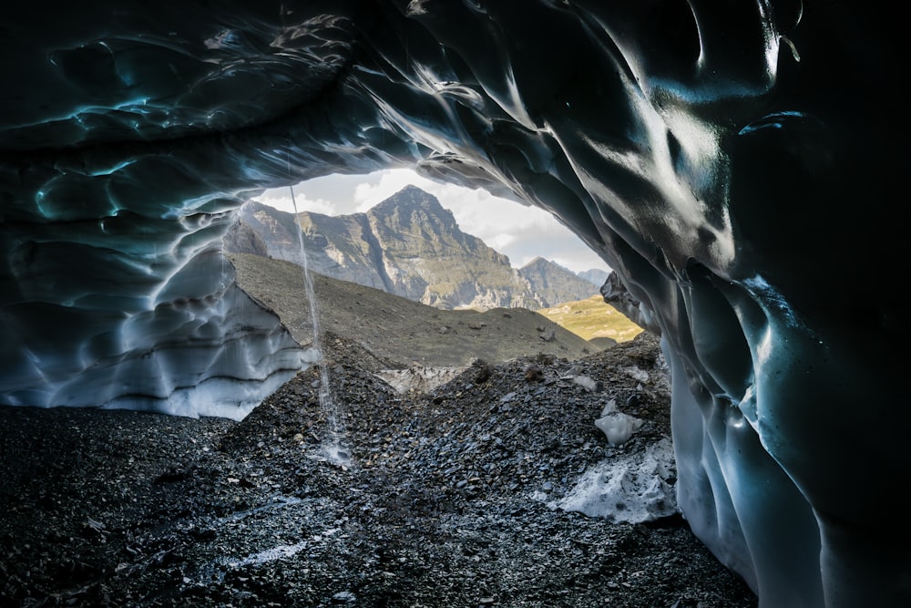 a large ice cave with mountains in the background