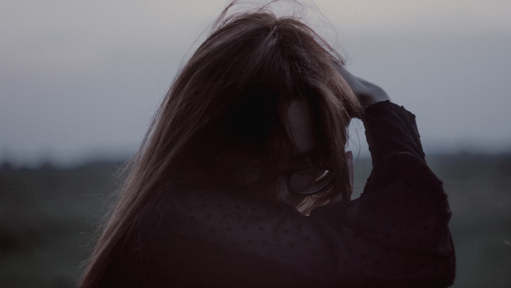 a woman with long hair standing in a field