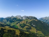 A panoramic view of the Pyrenees mountains with lush green valleys in Navarra under a bright blue sky.