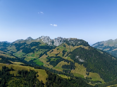A panoramic view of the Pyrenees mountains with lush green valleys in Navarra under a bright blue sky.