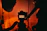 Close-up of a focused student adjusting camera settings in a dimly lit studio with warm orange accents.