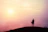 Person standing confidently on a hilltop at sunrise, symbolizing new beginnings