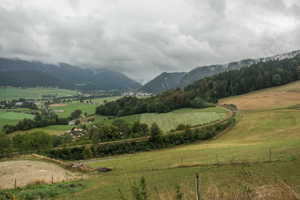 a lush green valley surrounded by mountains under a cloudy sky