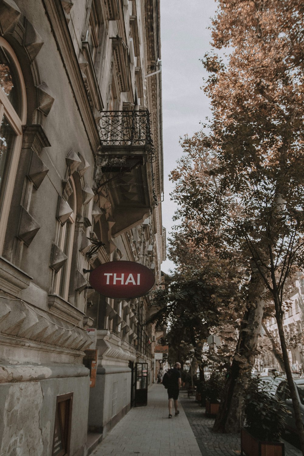 a person walking down a sidewalk next to a tall building