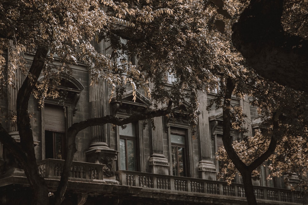 an old building with a balcony and trees in front of it