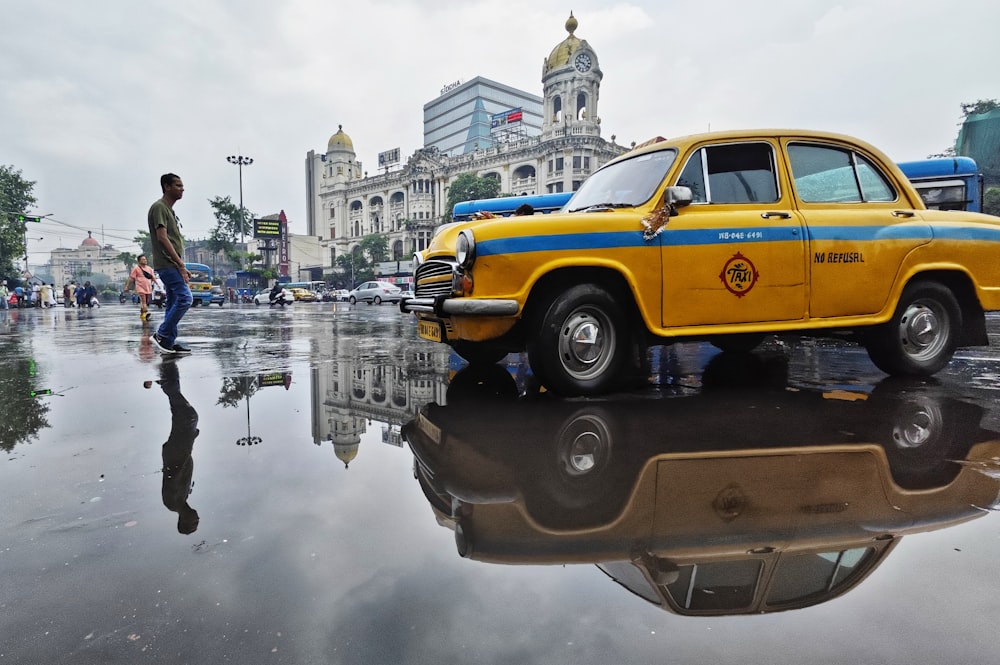a yellow taxi cab sitting on top of a puddle