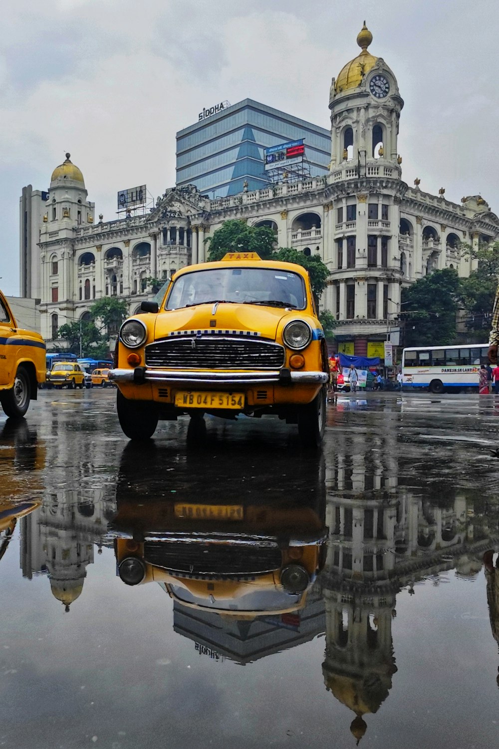 Ein gelbes Taxi fährt eine Straße neben einem hohen Gebäude entlang