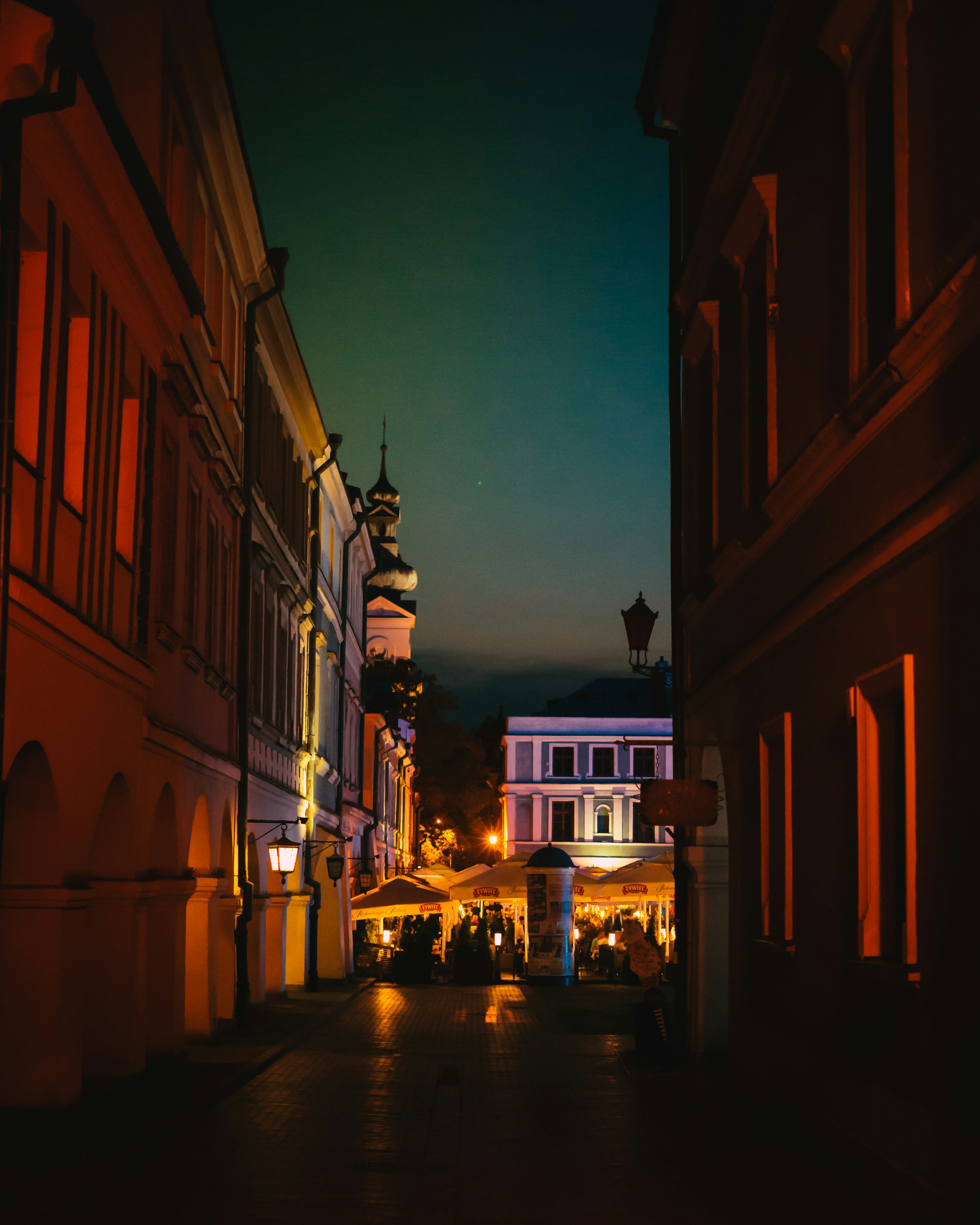 Une rue de la ville la nuit avec une tour de l’horloge en arrière-plan