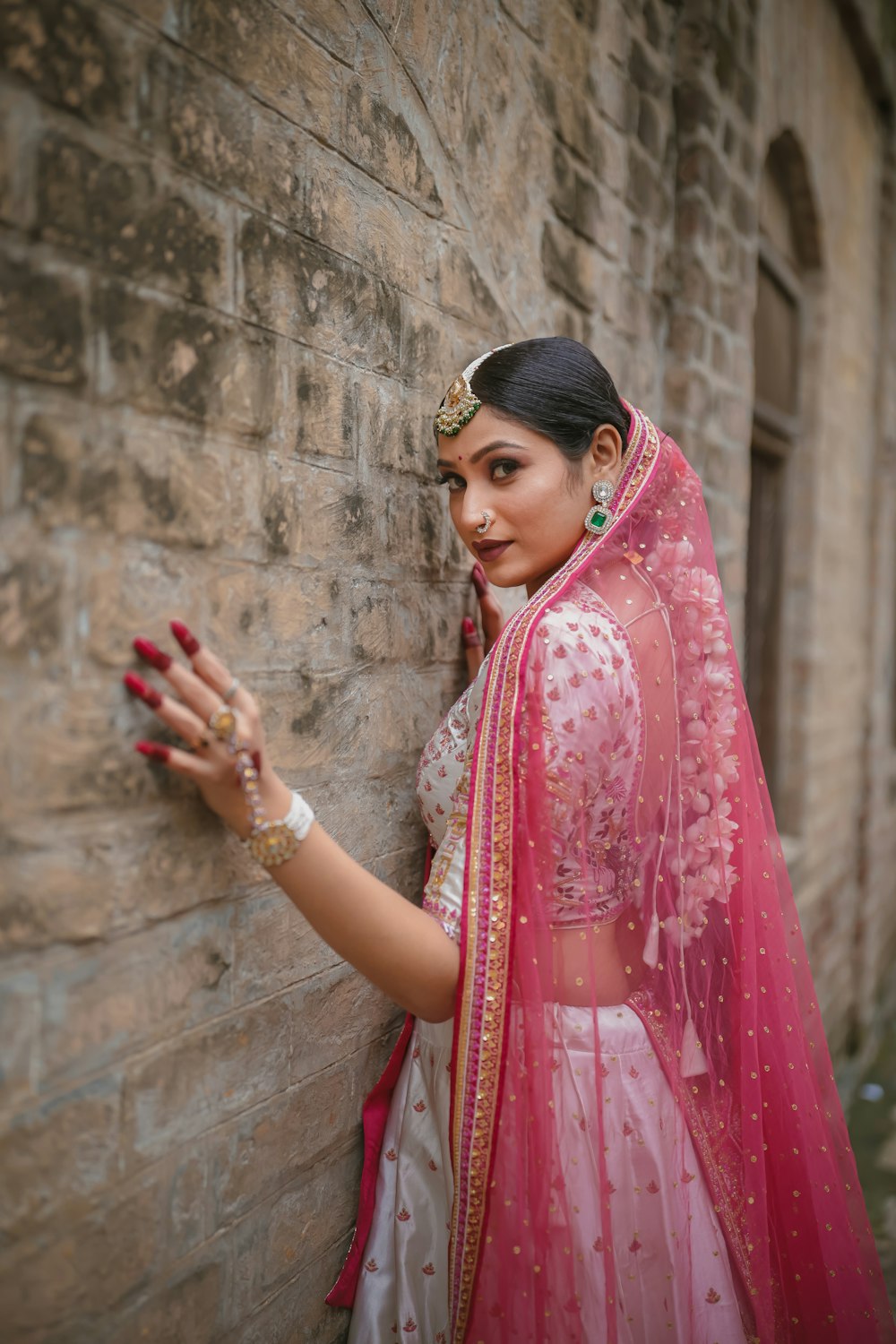 a woman in a red and white outfit leaning against a brick wall