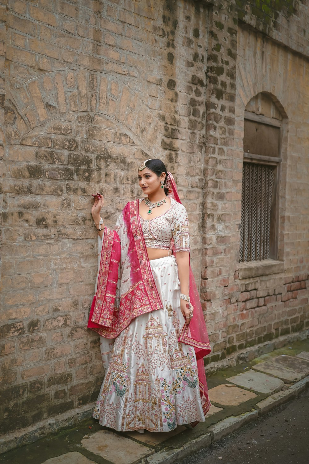 a woman standing next to a brick wall