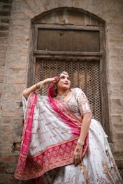 Model wearing a vibrant phulkari embroidered suit with pastel and gold accents, set against a Jaipur palace backdrop.