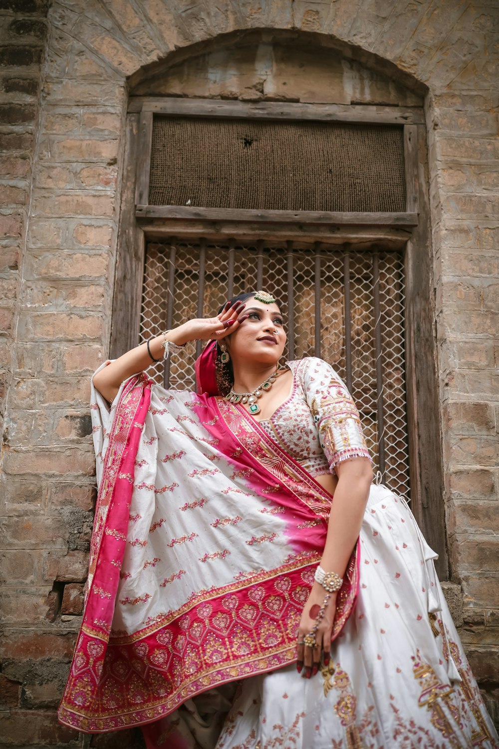 a woman in a white and pink lehenga