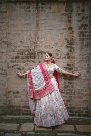 A model wearing a vibrant embroidered jacket inspired by traditional Mexican patterns, standing against a warm terracotta wall.