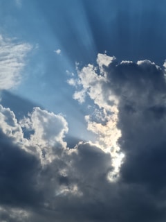 Close-up of sun rays piercing through a nebula’s colorful clouds.