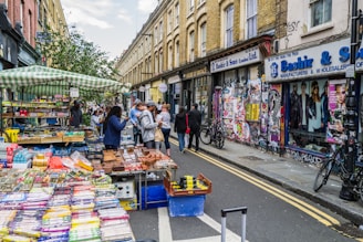 A lively street market in a neighborhood with colorful stalls and happy locals shopping.