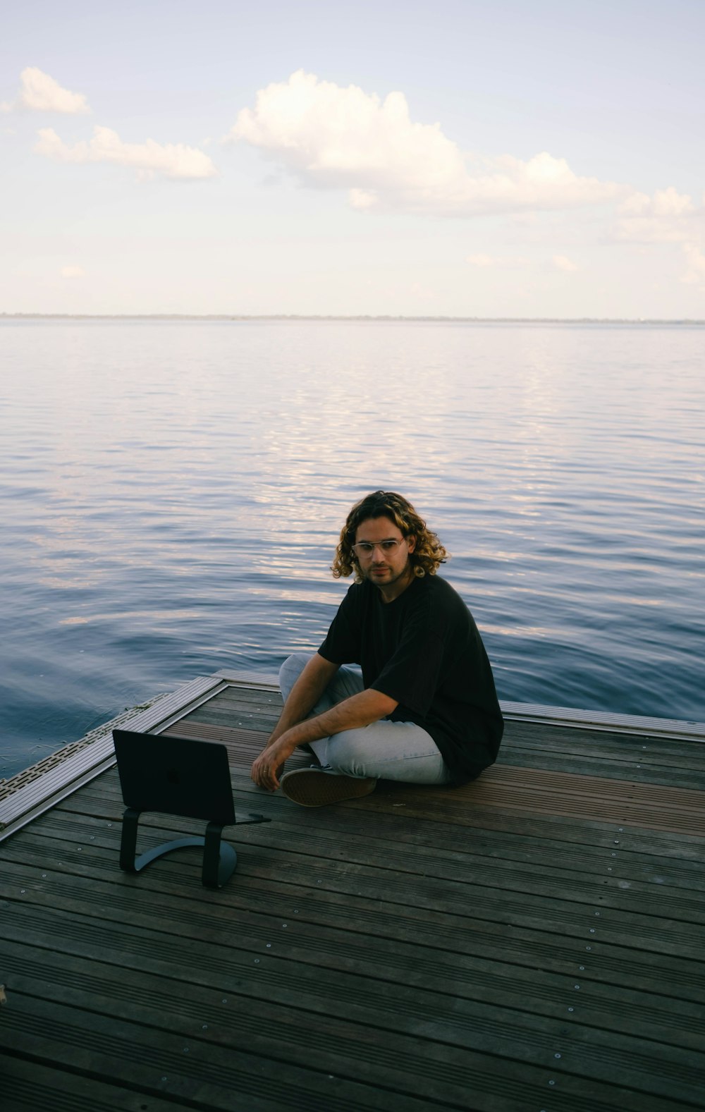 a man sitting on a dock with a laptop