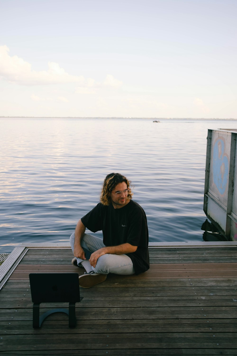 a man sitting on a dock next to a body of water