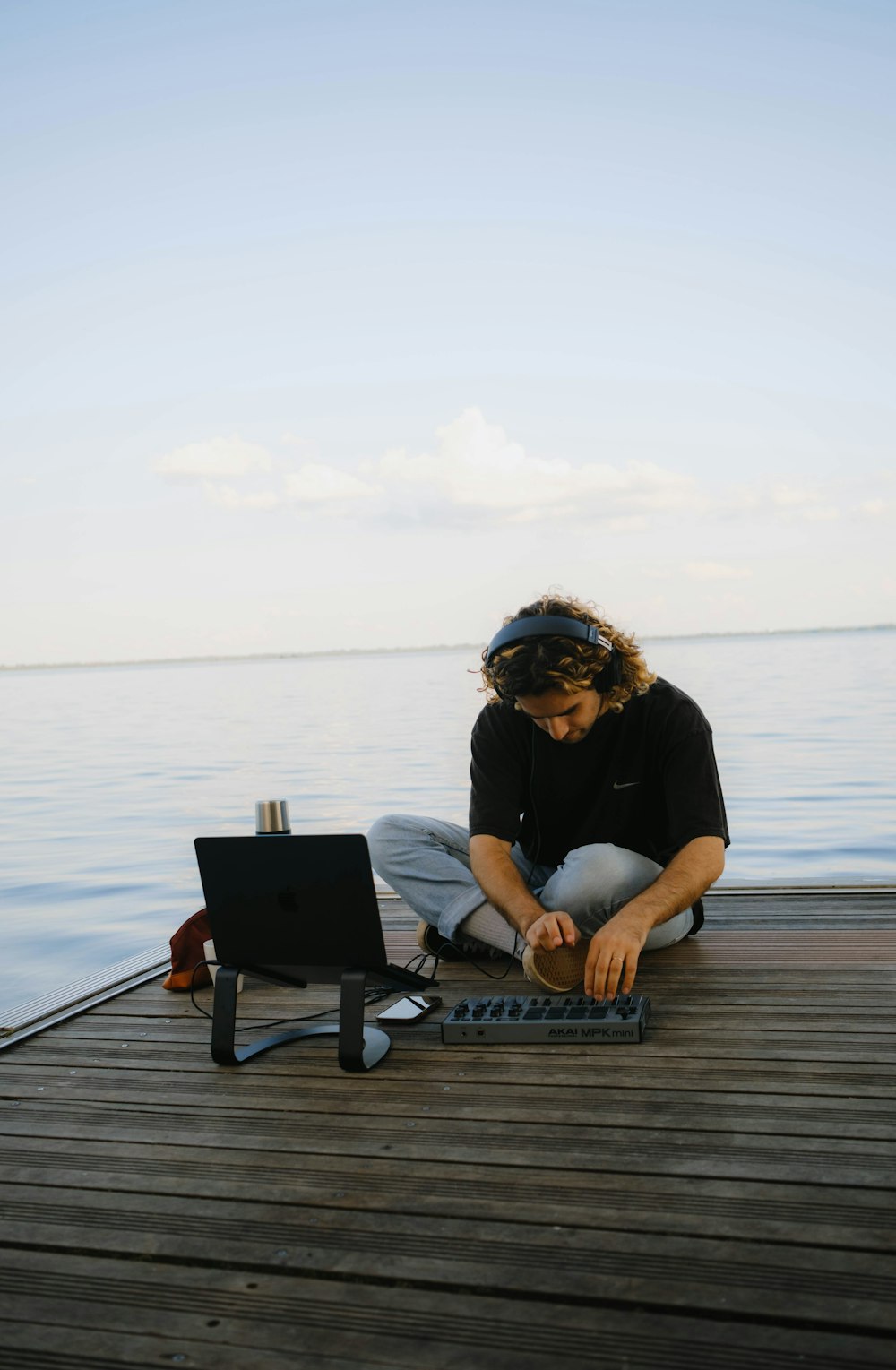 a man sitting on a dock working on a laptop