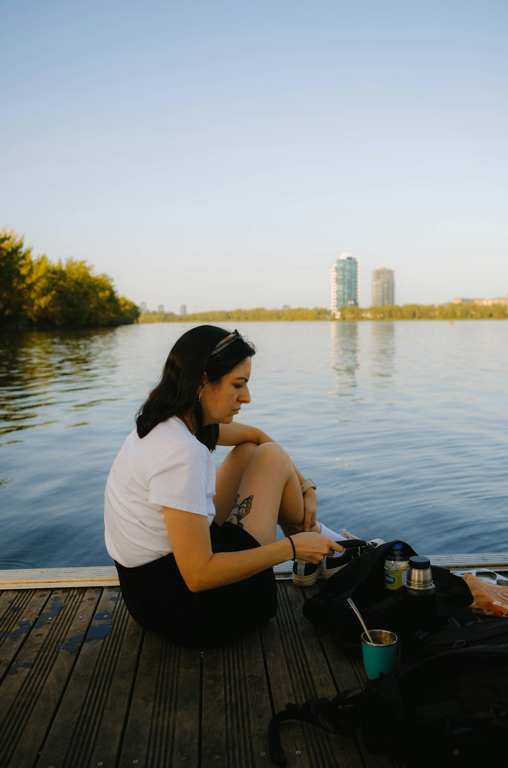 a woman sitting on a dock next to a body of water