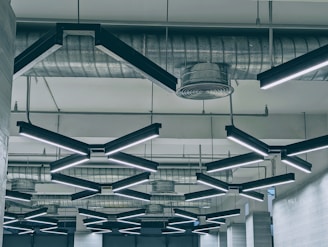 A professional electrician installing modern lighting fixtures in a commercial building.