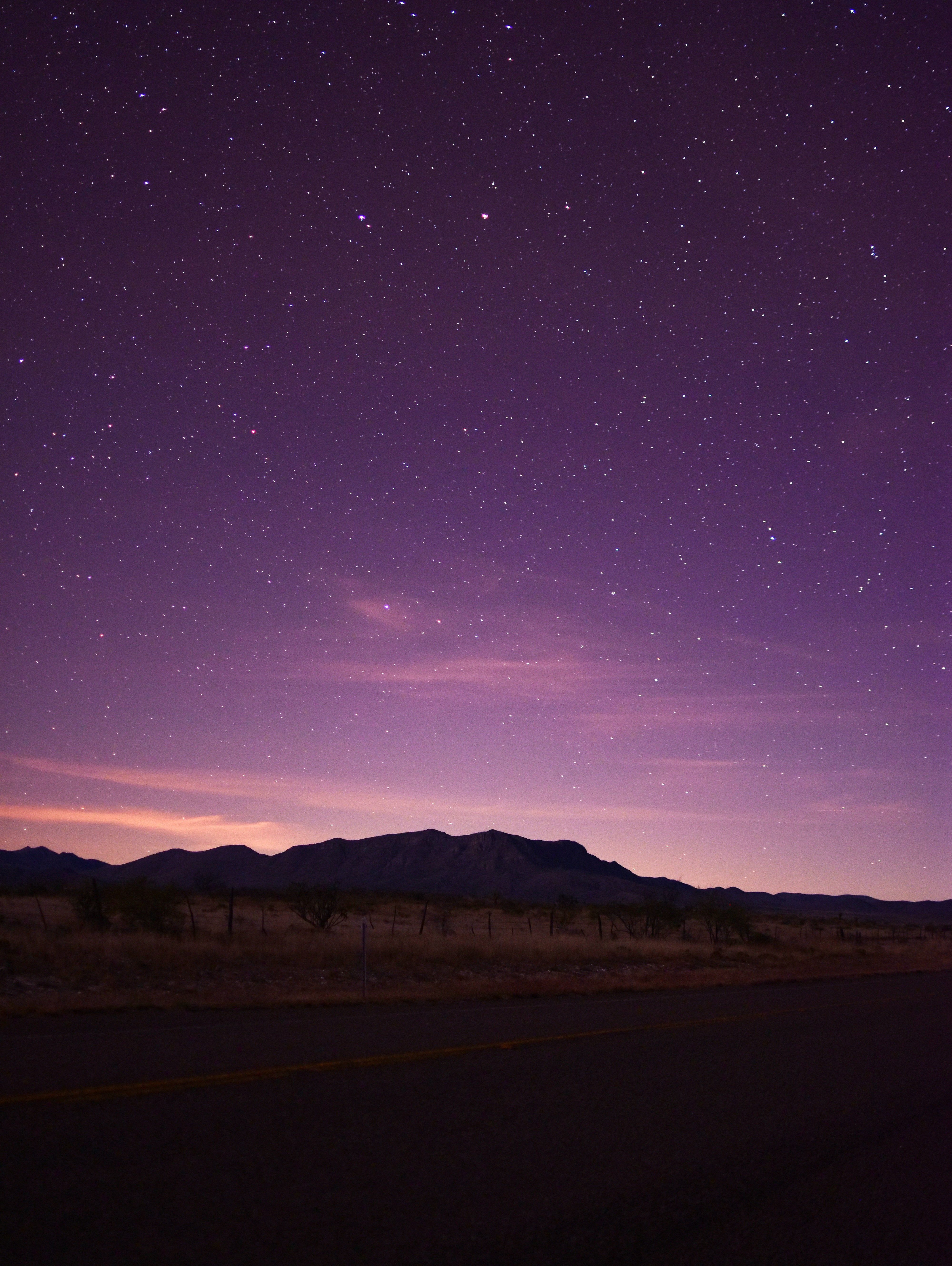 The night sky with stars and clouds above a road