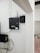 A security and access control system is mounted on a wall with visible wiring and electronic equipment. The ZKTeco brand is prominently displayed on the black access control box. Additional equipment is present, including a network switch with connected cables. There are paint supplies and a pink protective floor covering in the adjacent room.