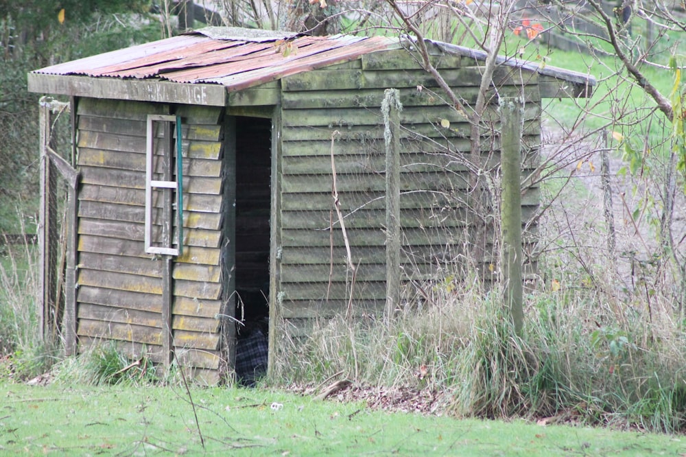 an outhouse in the woods with a rusty roof