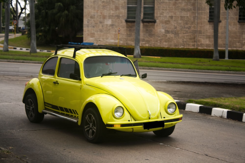 a yellow car driving down a street next to a tall building