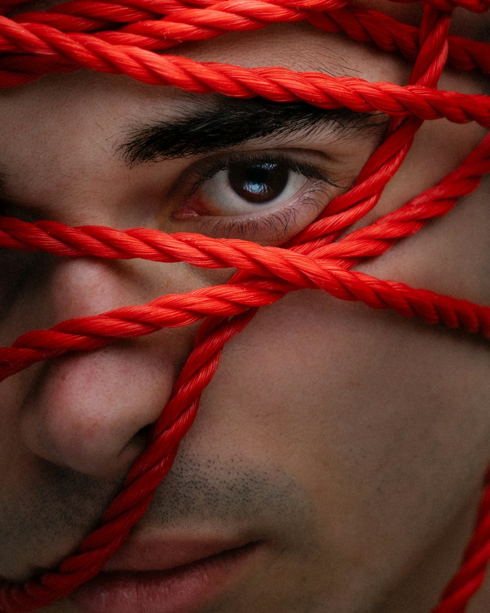 a close up of a man's face with red ropes on his face