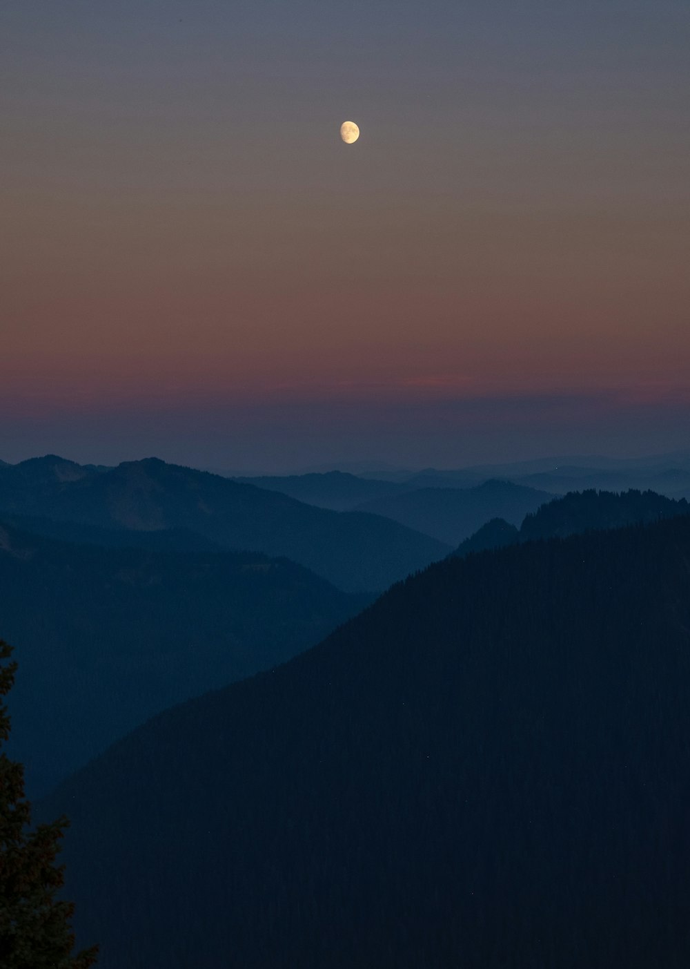 Se ve una luna llena sobre una cadena montañosa