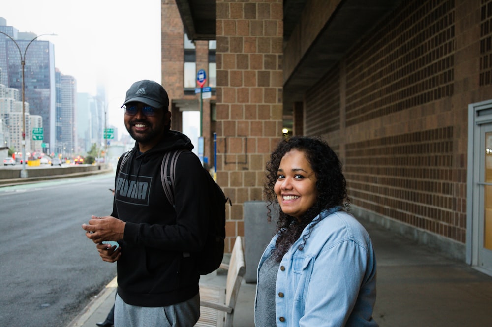 a man standing next to a woman on a sidewalk