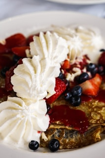 Close-up of fluffy waffles topped with fresh strawberries and whipped cream.
