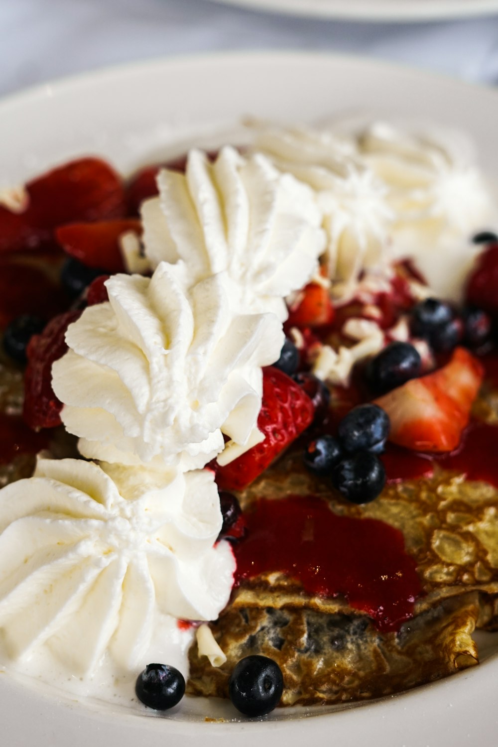 un plato blanco cubierto con panqueques cubiertos de fruta