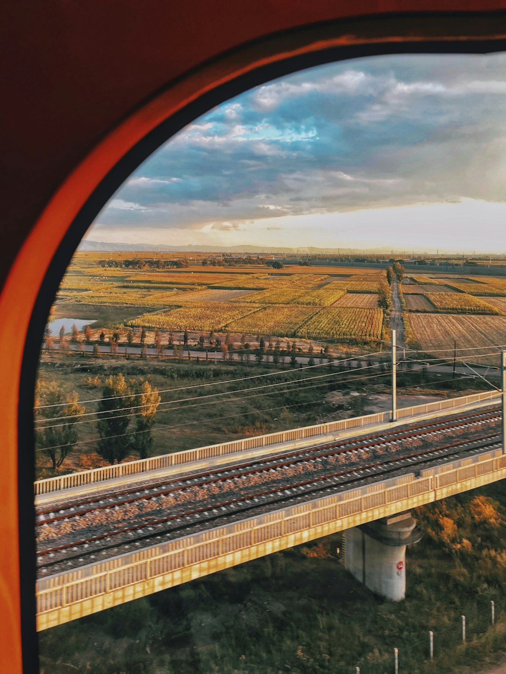 a train traveling over a bridge next to a lush green field