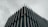 A modern building with a striking architectural design. Vertical metal or concrete fins protrude from the facade, creating an angular and geometric aesthetic. The overcast sky adds a moody and subdued background to the sharp, clean lines of the structure.