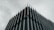 A modern building with a striking architectural design. Vertical metal or concrete fins protrude from the facade, creating an angular and geometric aesthetic. The overcast sky adds a moody and subdued background to the sharp, clean lines of the structure.