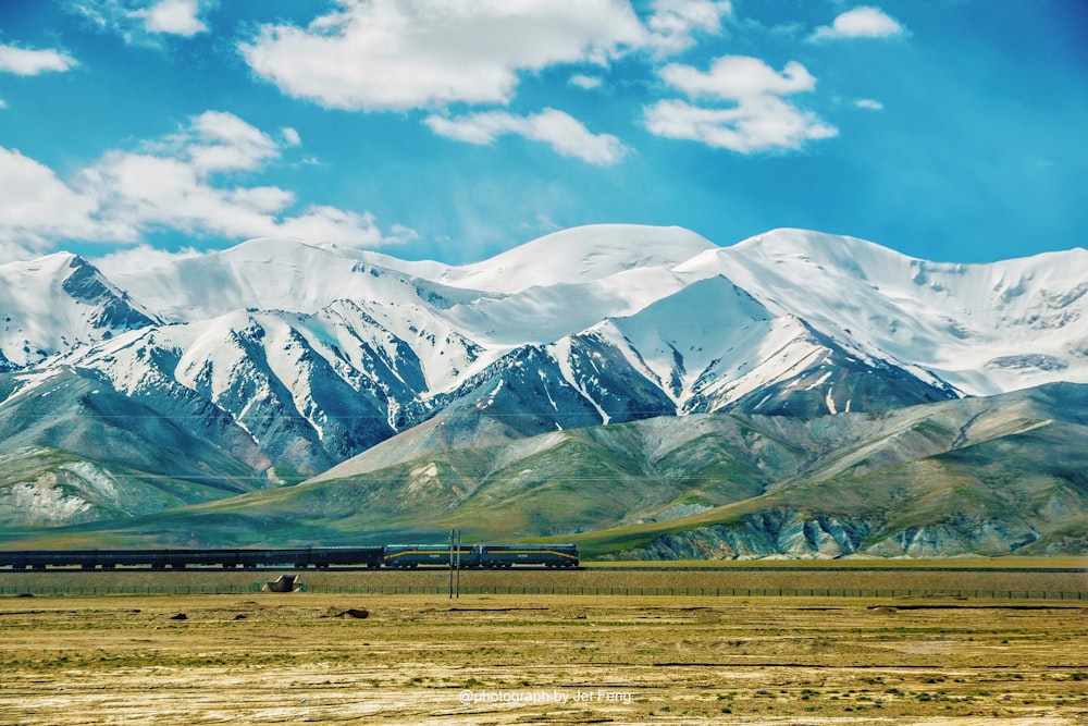 a train traveling through a rural countryside with mountains in the background