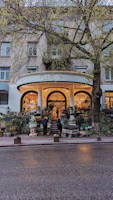 A charming commercial entrance framed by lush green planters bursting with vibrant flowers.