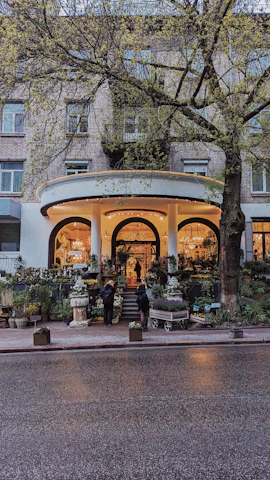 A charming commercial entrance framed by lush green planters bursting with vibrant flowers.
