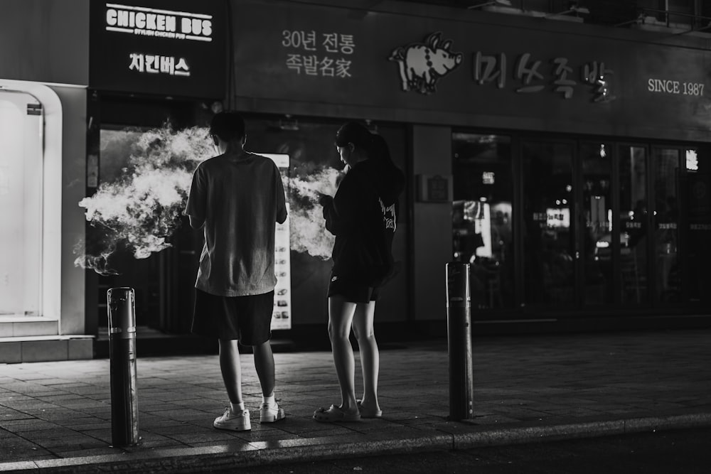 a man and a woman standing next to each other on a sidewalk