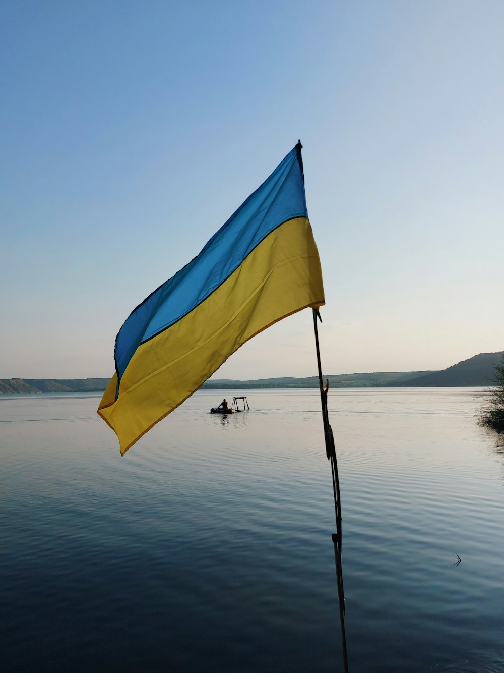 a blue and yellow flag on a pole in the water