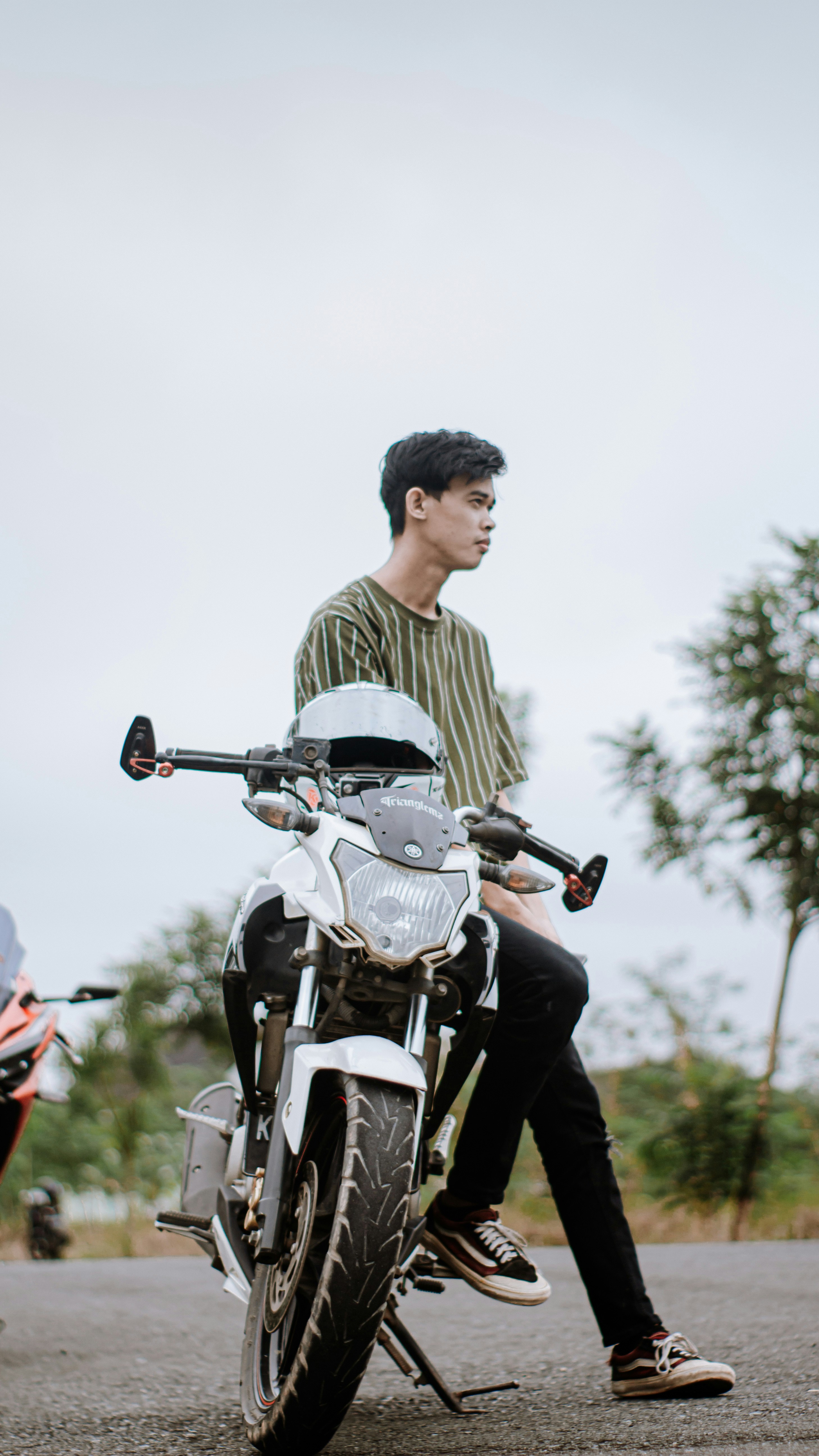 Seorang pria mengendarai sepeda motor putih